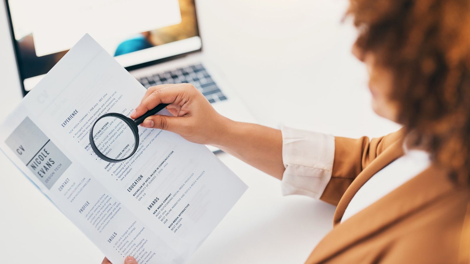 Recruiter screening a resume with a magnifying glass