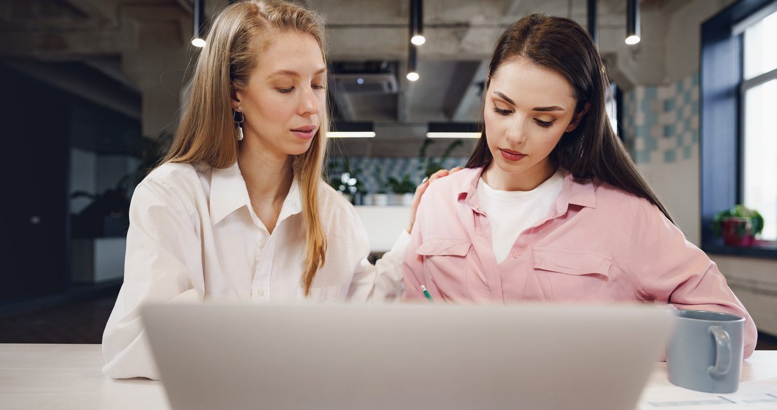Two women reviewing candidate profiles together on a laptop